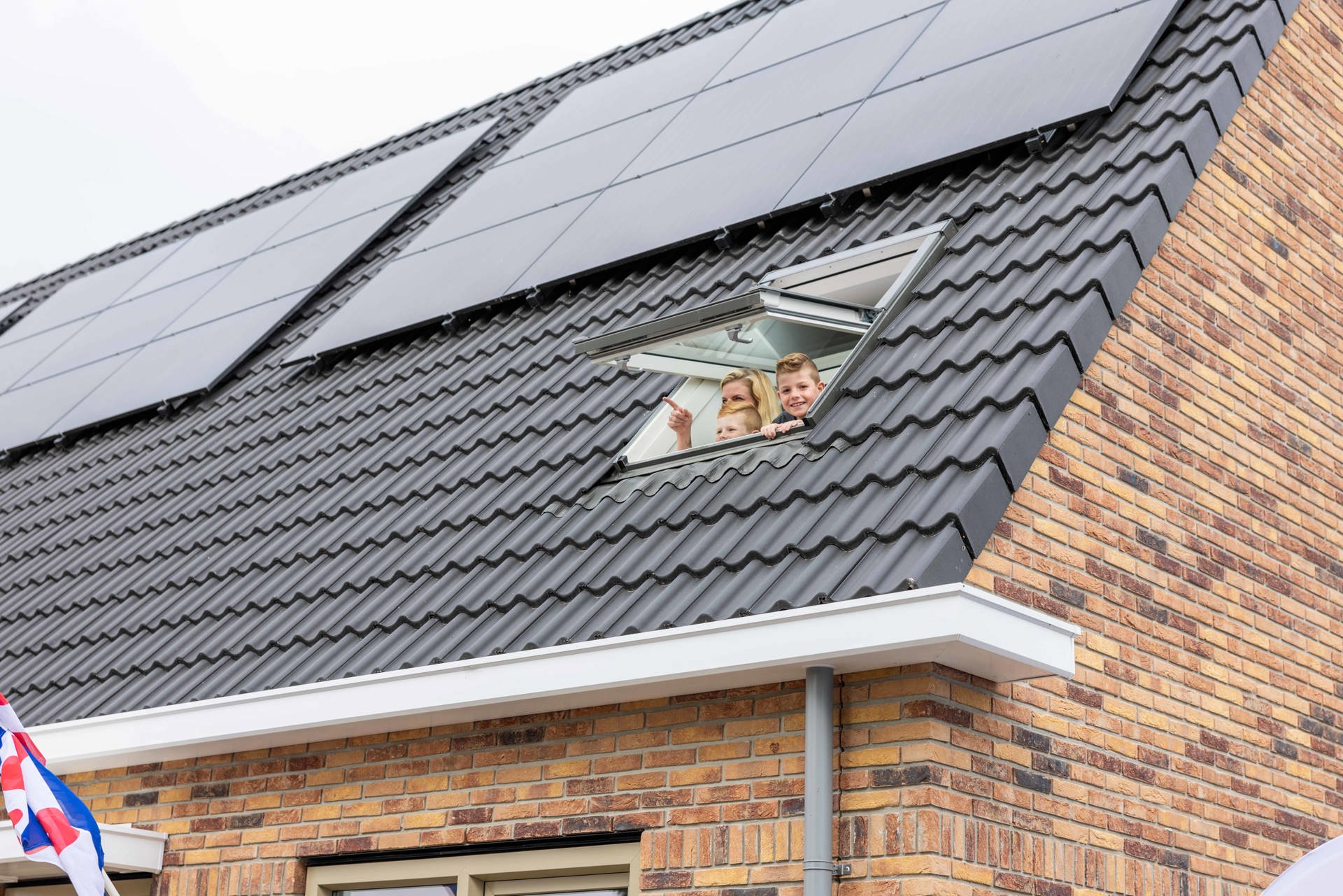 Kinderen kijken uit dakraam met zonnepanelen